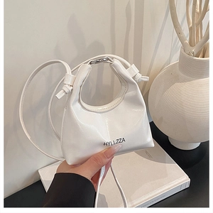 Dettaglio mini borsa a mezzaluna bianca in pelle verniciata lucida con anelli metallici
