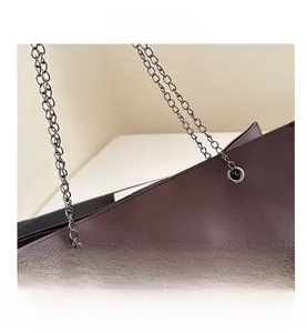 Dettaglio borsa tote in pelle marrone scuro con trama litchi e tracolla a catena in metallo