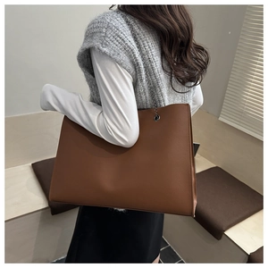 Dettaglio della borsa tote marrone in pelle martellata con tracolla a catena scura