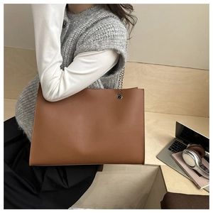 Borsa tote marrone in finta pelle con catena d'argento in un ambiente ufficio urbano