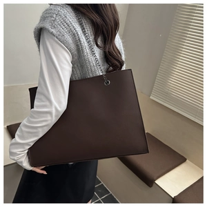 Vista laterale di borsa tote in pelle marrone scuro con tracolla a catena in metallo