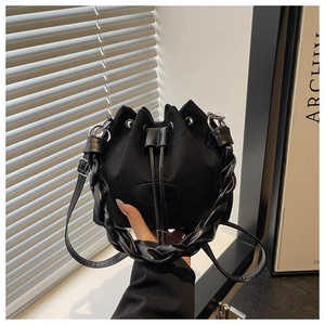 Detail of black suede bucket bag featuring woven leather handle and drawstring closure