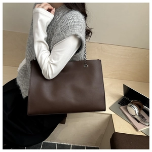 Vista laterale della borsa tote marrone scuro con catena in una scena di vita
