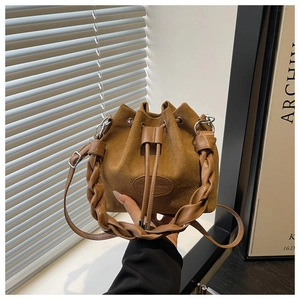 Detail of a brown suede bucket bag featuring a thick braided handle and drawstrings