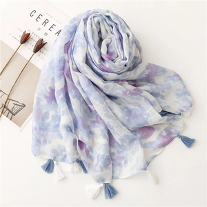 Detail of artistic floral scarf featuring blue and white fringe tassels and linen feel