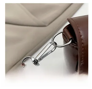 Detail of dark brown saddle bag showing polished silver metal swivel hook and leather strap