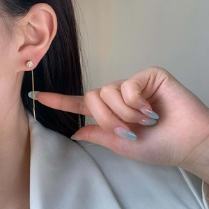 Elegant gold tassel earrings with sparkling zircon studs shown on a female model