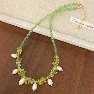 Collana di perline con pietre naturali verdi e perle barocche su sfondo rustico