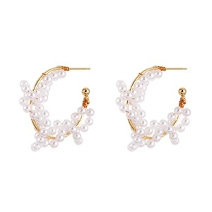 Détail de boucles d'oreilles créoles dorées en C ornées de grappes de perles blanches élégantes