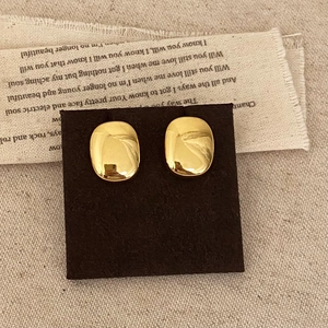 Boucles d'oreilles ovales dorées minimalistes avec finition miroir sur carte de présentation