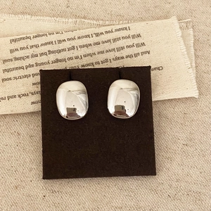 Boucles d'oreilles géométriques minimalistes en argent poli sur fond de lin naturel