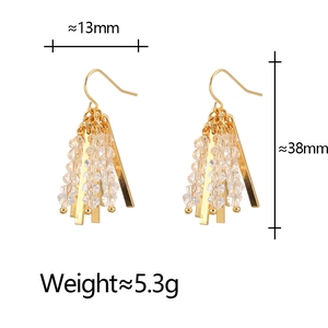 Close-up of gold tassel drop earrings with crystal beads and rectangle bar detail