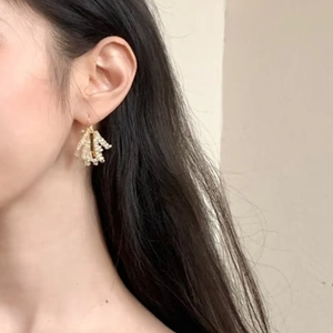 Elegant crystal tassel earrings with white beads and gold metal accents on model