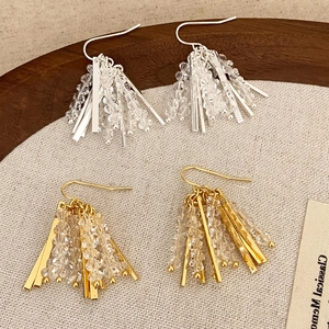 Chic crystal tassel earrings in gold and silver colors on minimalist fabric background