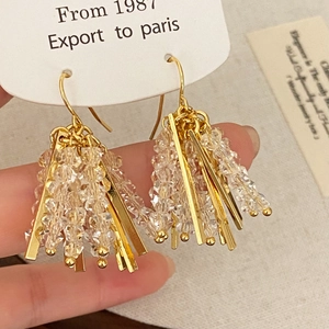 Detail view of crystal tassel earrings with gold metal strips on display card