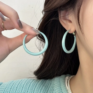 Gros plan de boucles d'oreilles rondes vert menthe avec finition brillante sur un modèle