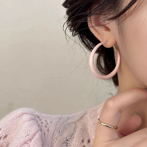 Créoles roses d'été minimalistes et bague dorée portées par un mannequin sous lumière douce