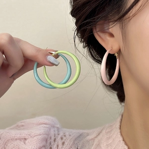 Gros plan de grandes boucles d'oreilles créoles colorées en rose, bleu et vert