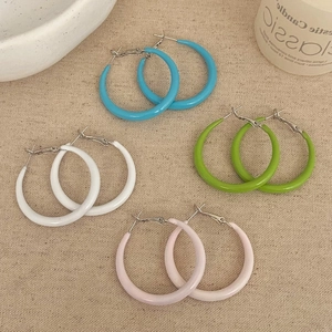 Gros plan de quatre paires de créoles aux couleurs bonbon en bleu, vert, blanc et rose
