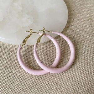 Vue détaillée de boucles d'oreilles créoles roses sur un socle en marbre blanc poli