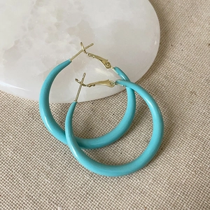 Détail de créoles bleu Tiffany sur plateau en marbre avec crochet en métal doré