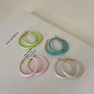 Vue à plat de créoles colorées en émail dans les tons vert pastel, bleu, rose et beige