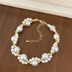 Elegant pearl bracelet with gold beads and lobster clasp on dark wooden background
