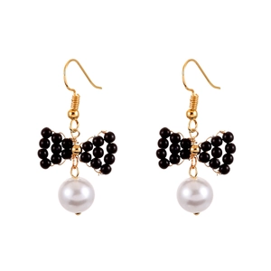 Boucles d'oreilles nœud noir élégantes avec perles blanches et crochets dorés sur blanc