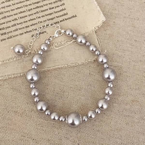 Elegant silver pearl bracelet with adjustable lobster clasp on vintage linen backdrop