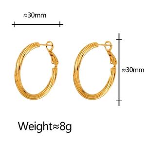 Macro detail of gold 30mm hoop earrings with a textured ribbed finish and luxury design