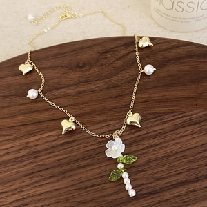 Collier élégant à fleurs dorées avec perles et pendentifs cœur sur support en bois