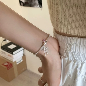 Close-up of a silver bow necklace with pearl and pink gem on a woman's neck
