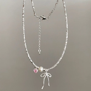 Detailed shot of bow-knot necklace with white pearl and pink heart pendant