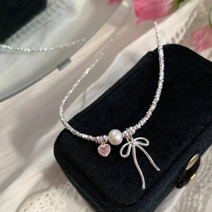 Detail of silver bead necklace with pink heart crystal, white pearl and bow pendant