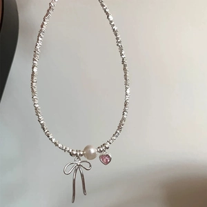 Detail of beaded necklace with irregular silver beads, white pearl and pink heart pendant