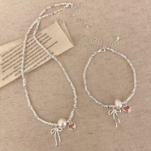 Detail of silver bow necklace and bracelet set with white pearl and pink heart crystal