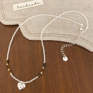 Détail du collier de perles avec pendentif cœur incrusté de perles sur bois et tissu