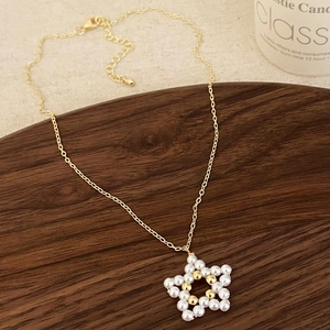 Collana a catena dorata con ciondolo a stella in perle fatto a mano su vassoio in legno