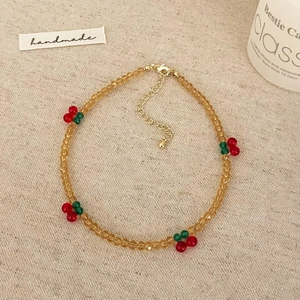 Détail du collier de perles ambrées facettées avec petits motifs de cerises