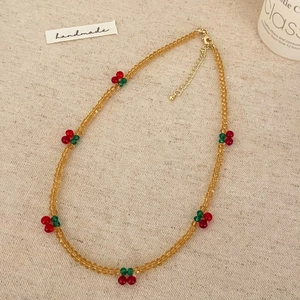 Collier artisanal en perles ambrées avec breloques cerises sur un fond de lin naturel