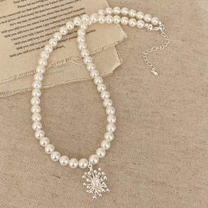 Elegant pearl necklace with snowflake pendant and sparkling zircon center on a vintage background