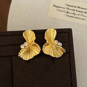 Elegant gold fan-shaped stud earrings with zircon stones on a vintage brown velvet display