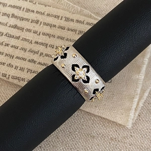 Macro detail of retro wide band ring with silver finish and black enamel floral patterns