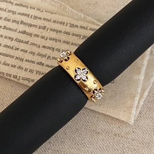 Macro shot of gold-brushed wide ring with sparkling zircon four-leaf clover details