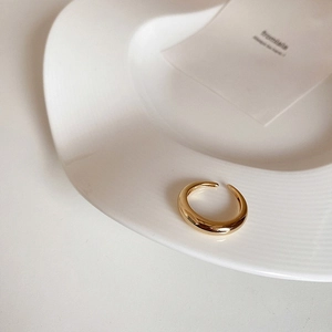Detailansicht eines polierten goldenen offenen Rings auf einem Keramikteller
