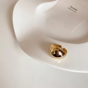 Nahaufnahme eines breiten goldenen gewölbten Rings mit poliertem Spiegelglanz auf Keramik
