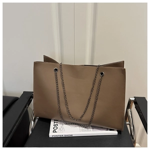 Dettaglio di una borsa tote marrone in pelle con catena in metallo grigio su sedile nero