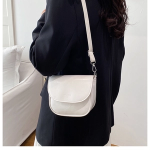Detail of a creamy white half-moon crossbody bag with embossed logo and silver hardware