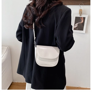Lifestyle view of a minimalist white glossy leather semi-circle crossbody bag on model