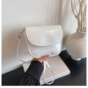 Detail of white patent leather saddle bag with glossy finish and brand logo